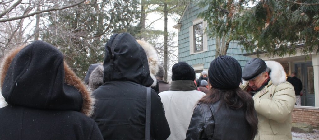 people standing outside of home waiting for sale to start