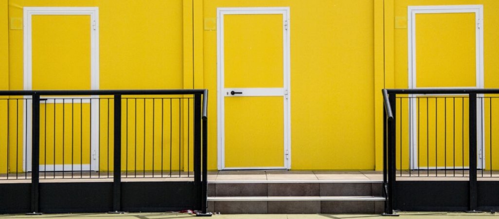 yellow building with doors and black railing