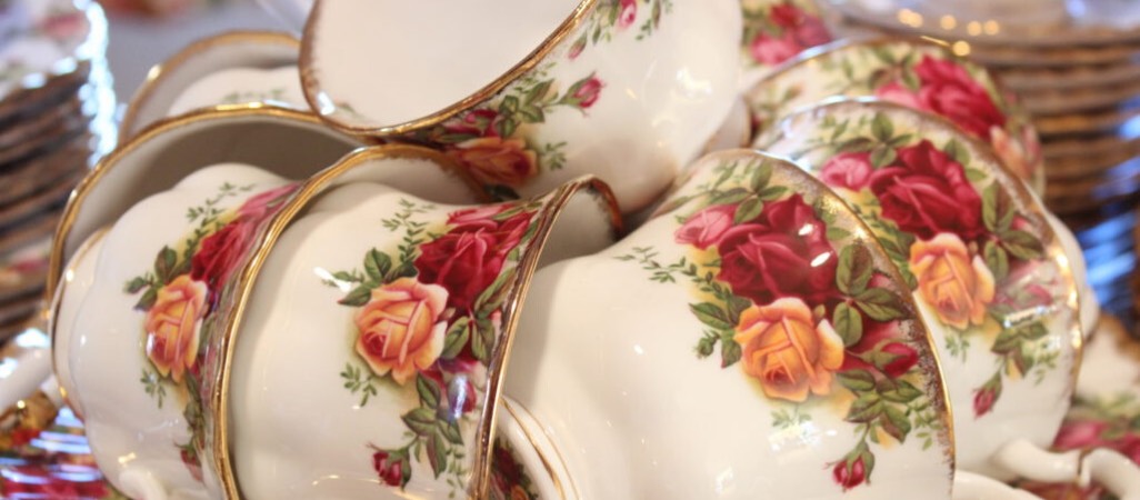 gold rimmed teacups with red, peach, and pink roses