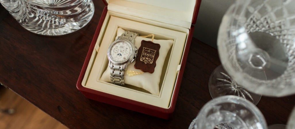 Zenith watch inside of a box next to crystal wine glasses