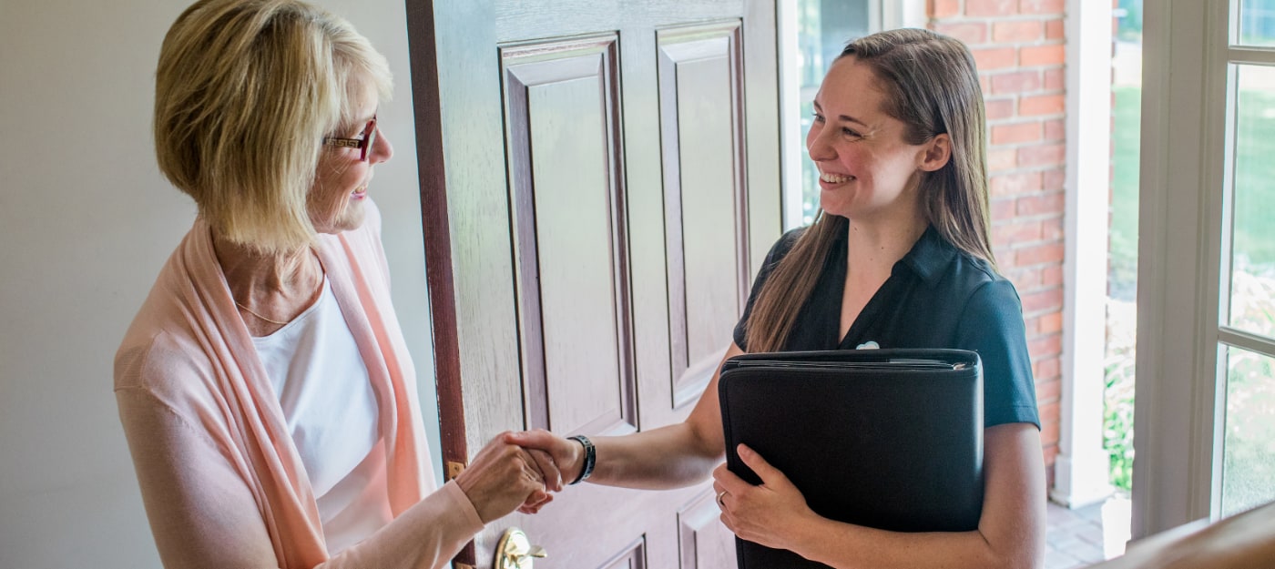 Allison Ruby of Poof Estate Services shakes customer's hand in house doorway