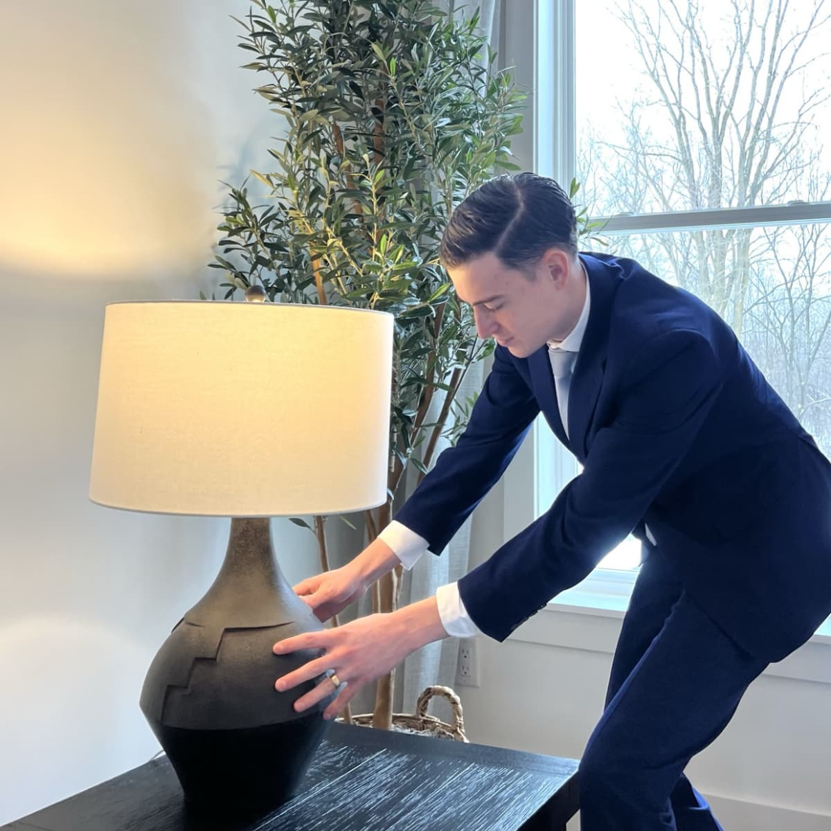 Poof staff member wearing a suit and positioning a lamp on a table