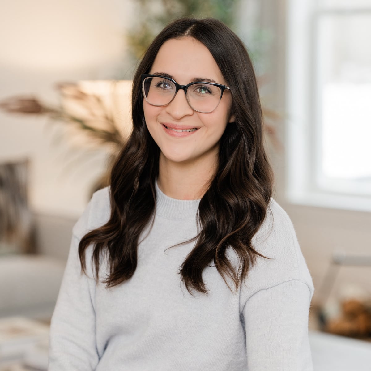 Marissa Paponetti, Administrator and IT for Poof Estate Services; smiling woman with long wavy brown hair and top-rimmed glasses